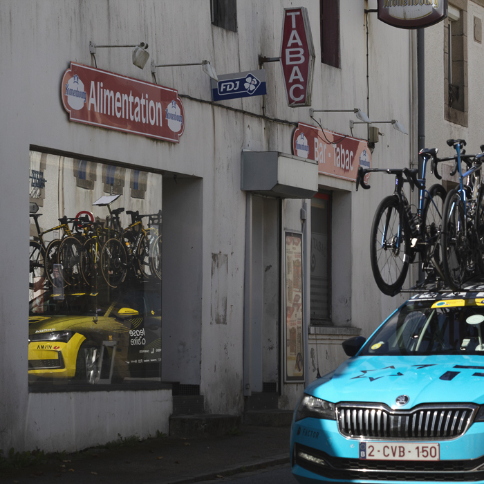 Bretagne Classic - Ouest-France 2025 - Reflections of team cars are seen in the window of a Tabac in Le Saint