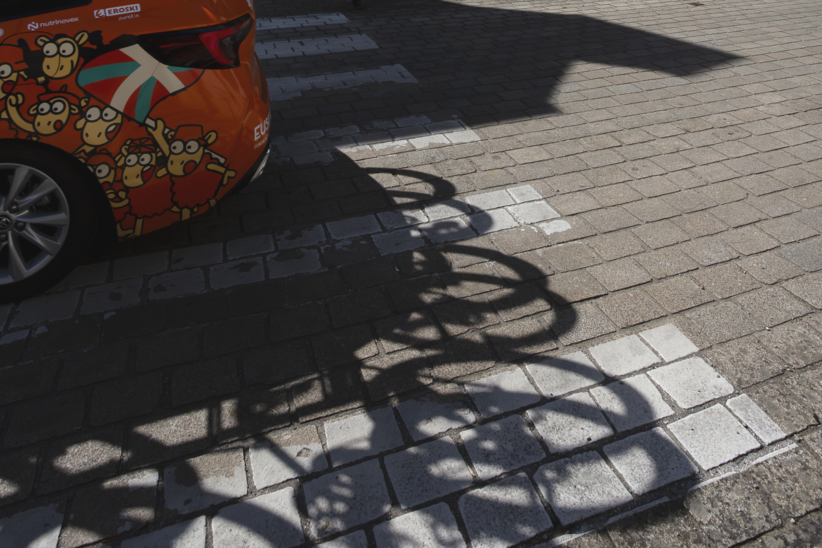 Bretagne Classic - Ouest-France 2025 - Shadows of bikes are cast on the road from the Euskaltel - Euskadi team car on which Cartoon sheep are depicted waving the Basque flag