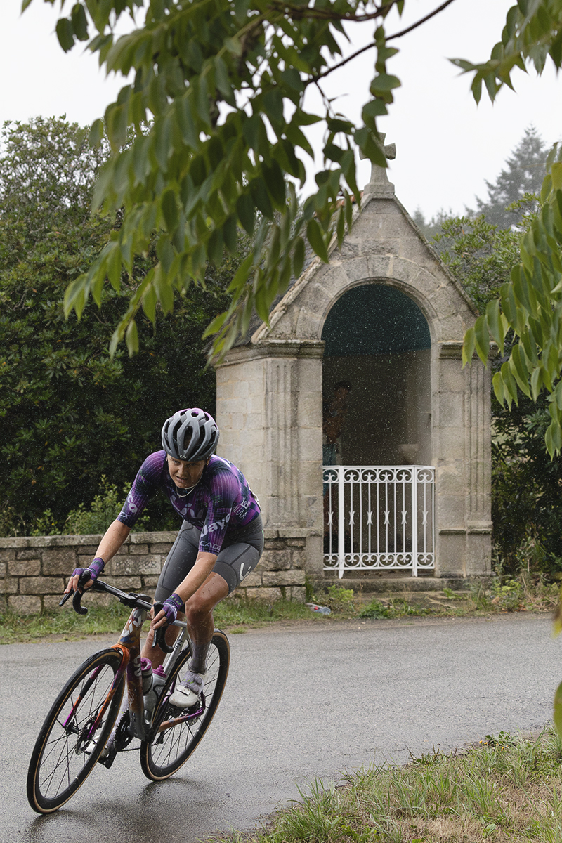 Classic Lorient Agglomération - Ceratizit 2025 - Jeanne Korevaar rides round a corner with a small roadside shrine in the background