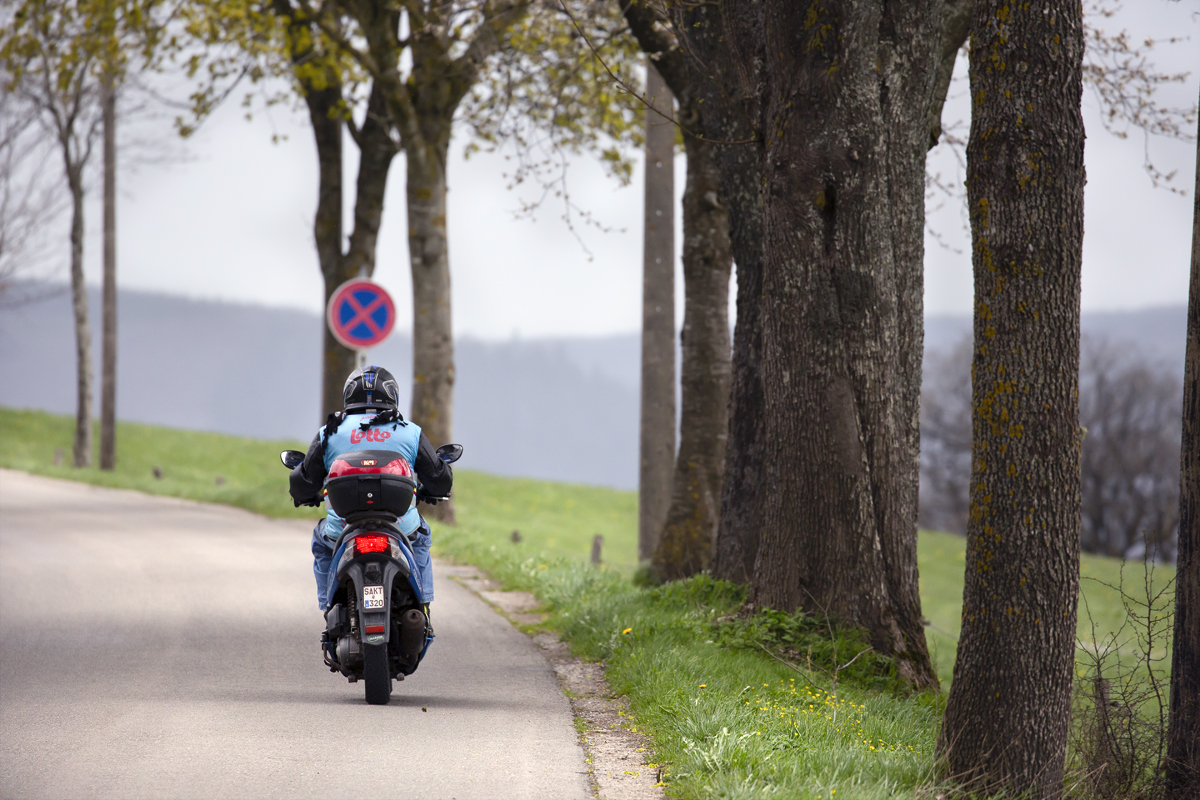 Liège-Bastogne-Liège 2023 - A race steward on a moped wearing a Belgium cycling vest makes his way home after the race