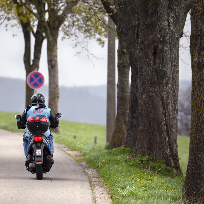 Liège-Bastogne-Liège 2023 - A race steward on a moped wearing a Belgium cycling vest makes his way home after the race