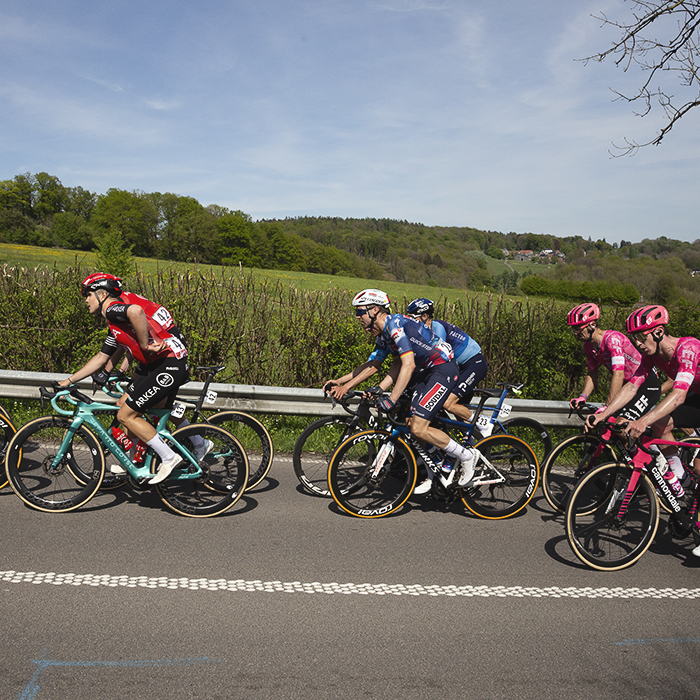 Liege Bastogne Liege 2025 - A group of riders pass a vista of open fields on Côte des Forges