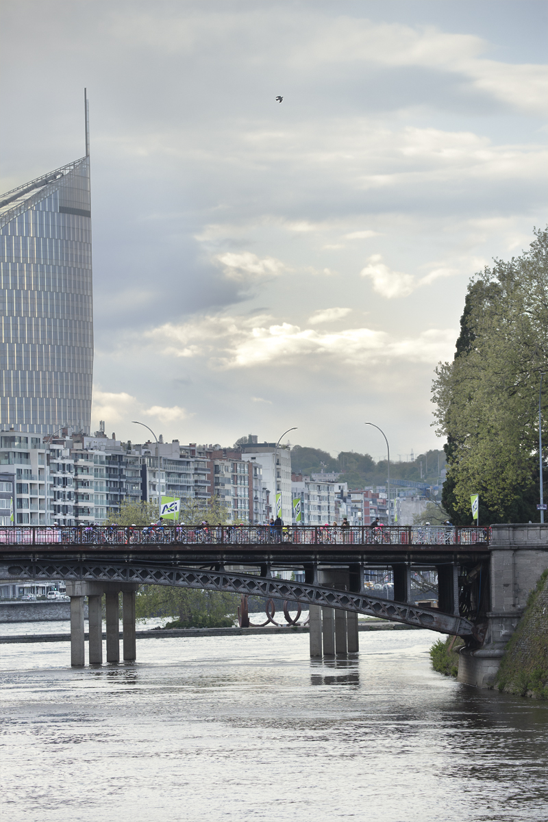 Liège-Bastogne-Liège Femmes 2024 - Riders on a bridge in Liège with the city behind them