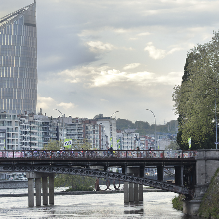 Liège-Bastogne-Liège Femmes 2024 - Riders on a bridge in Liège with the city behind them
