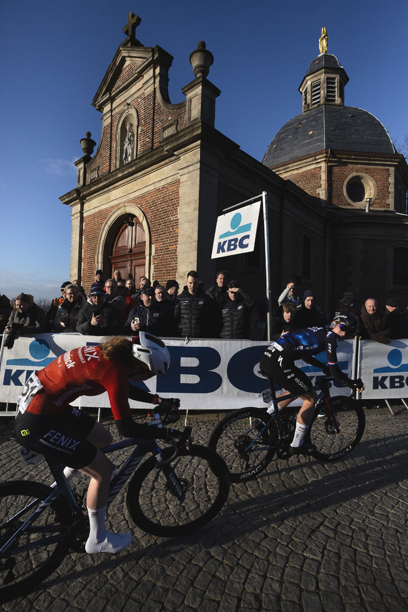 Omloop Nieuwsblad Vrouwen 2025 - Demi Vollering looks over her shoulder at Puck Pieterse at the summit of the Muur van Geraardsbergen
