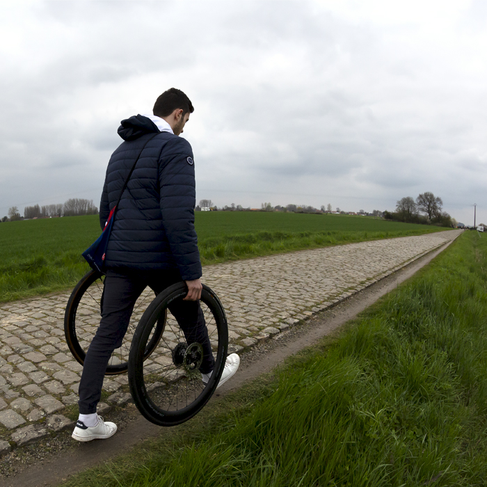 Paris Roubaix Femmes 2023 - A soigneur with wheels for the riders passes by