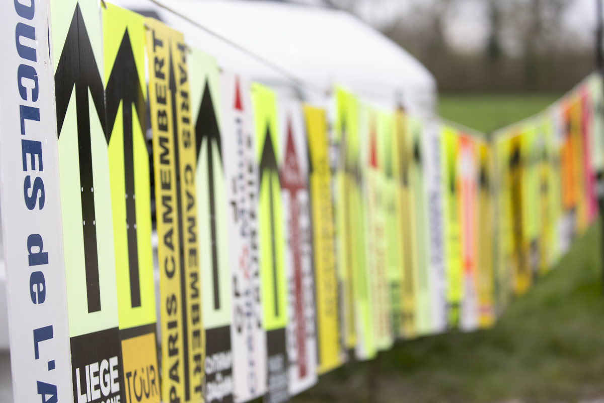 Paris Roubaix Femmes 2023 - Way markers from other races are displayed by fans at the side of the race