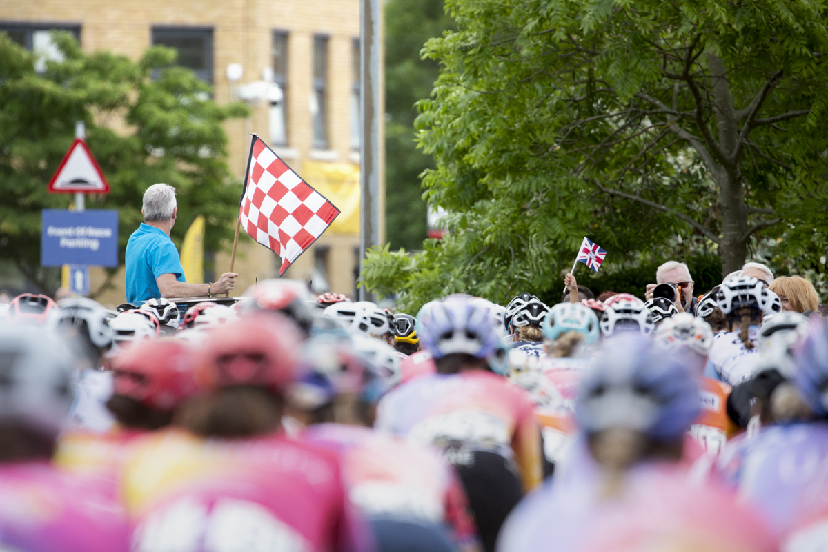 RideLondon Classique 2022 - A red and white chequered flag is waved for the start of the race at Anglia Ruskin University