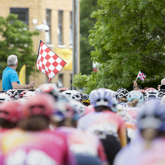 RideLondon Classique 2022 - A red and white chequered flag is waved for the start of the race at Anglia Ruskin University