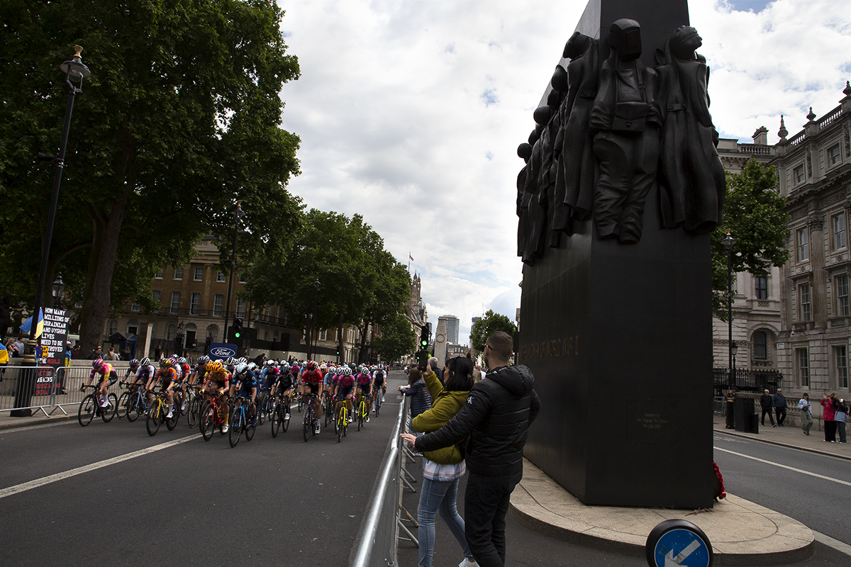 RideLondon Classique 2022 - The peloton passes the Women of WWII Monument as spectators film on their phones