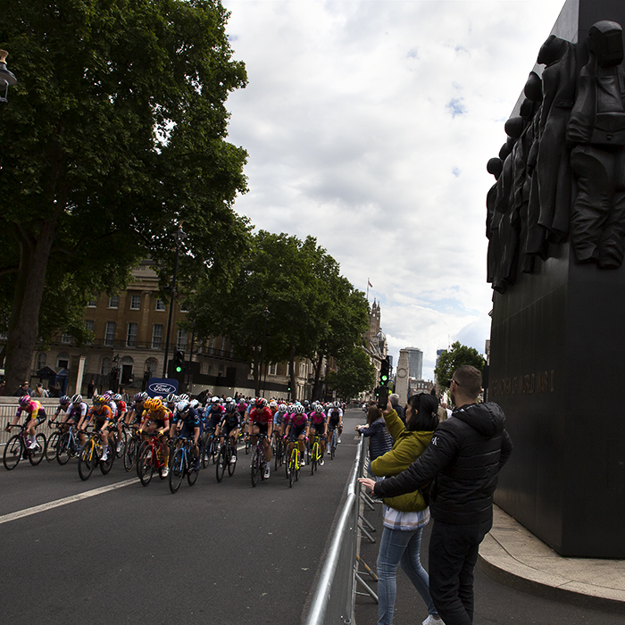 RideLondon Classique 2022 - The peloton passes the Women of WWII Monument as spectators film on their phones