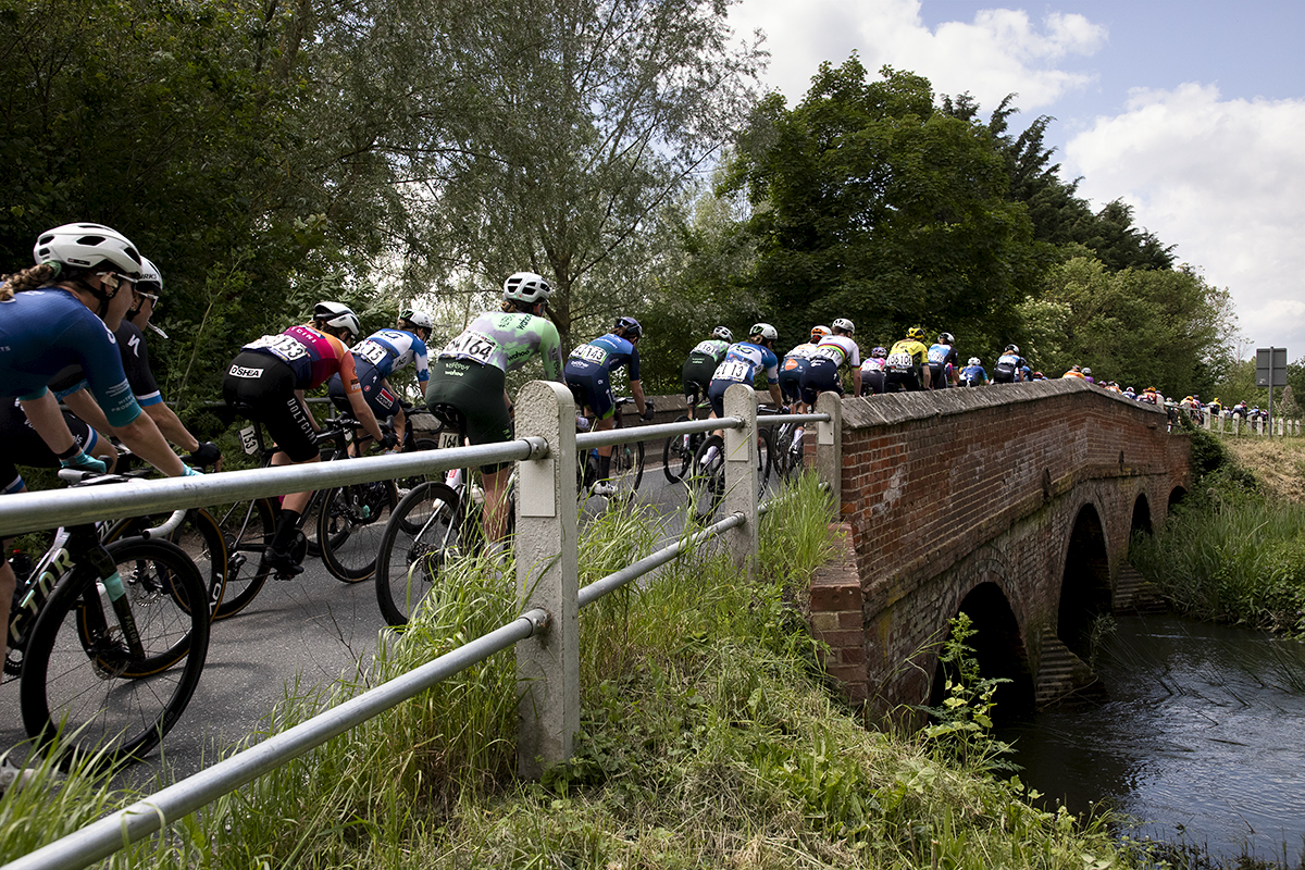 RideLondon Classique 2024 - The race crosses a brick bridge over a small river at Blue Mills