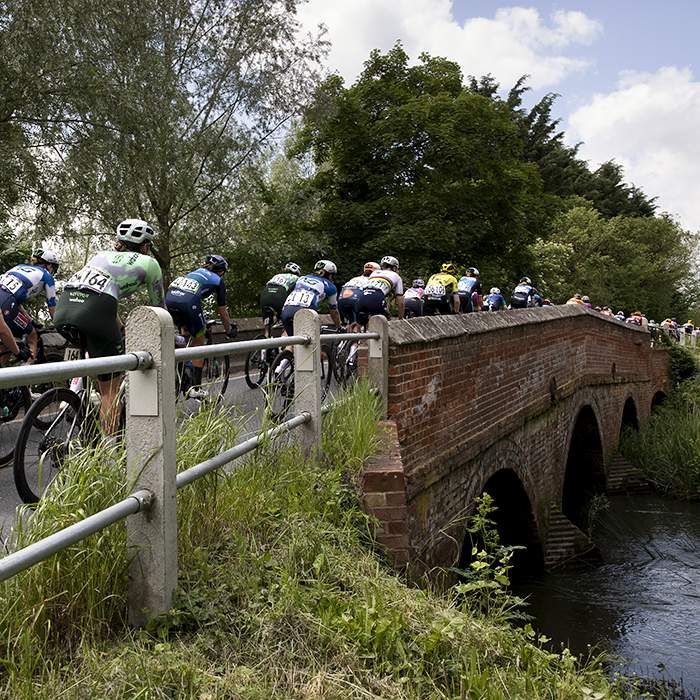 RideLondon Classique 2024 - The race crosses a brick bridge over a small river at Blue Mills