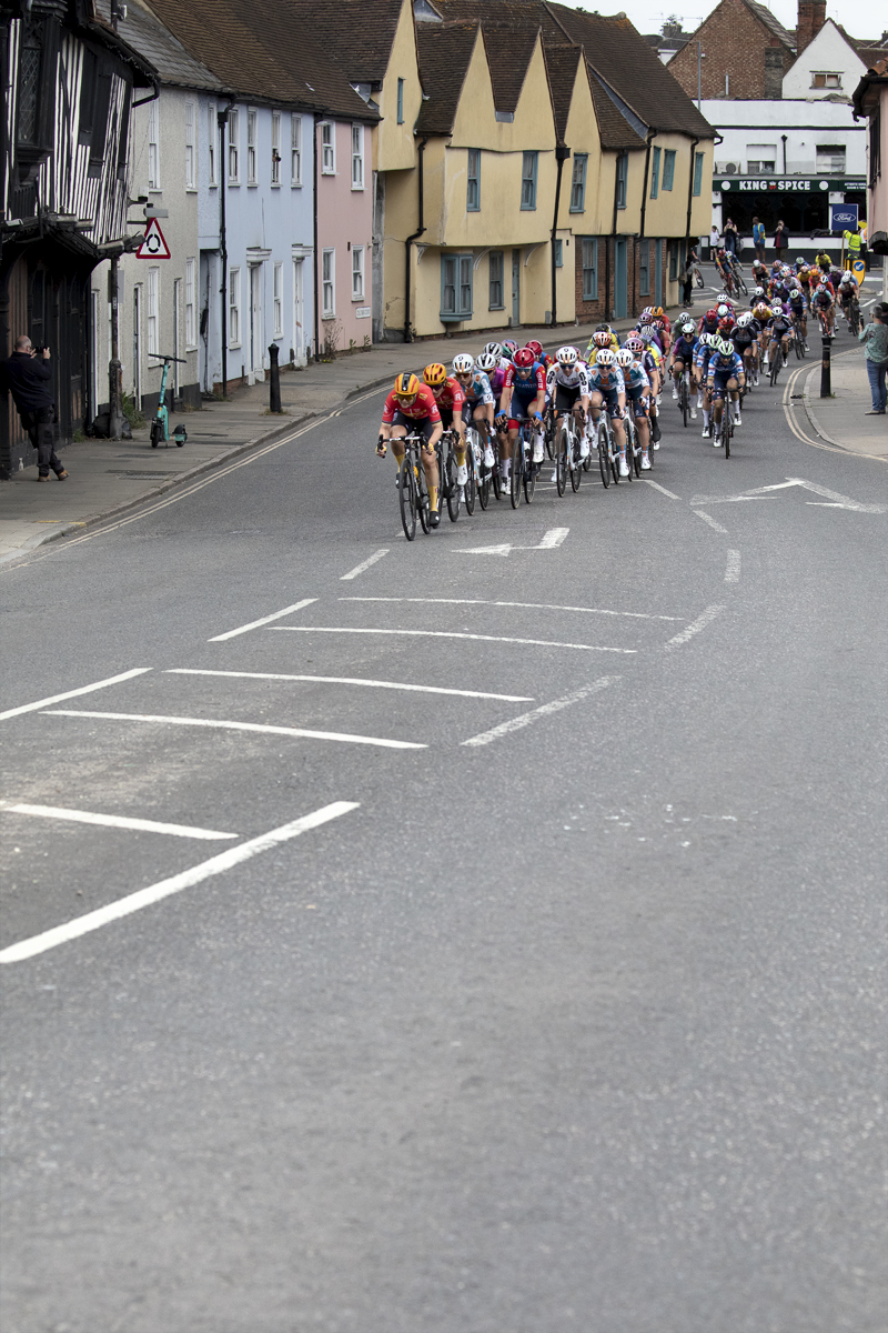 RideLondon Classique 2024 - Riders pass by a row of brightly painted houses in Colchester