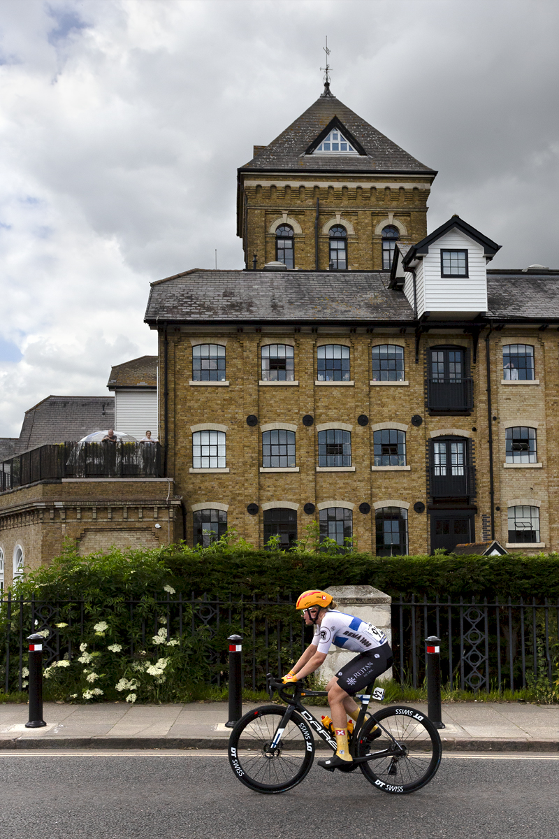 RideLondon Classique 2024 - Uno-X Mobility rider Anniina Ahtosalo passes by a mill building in Colchester