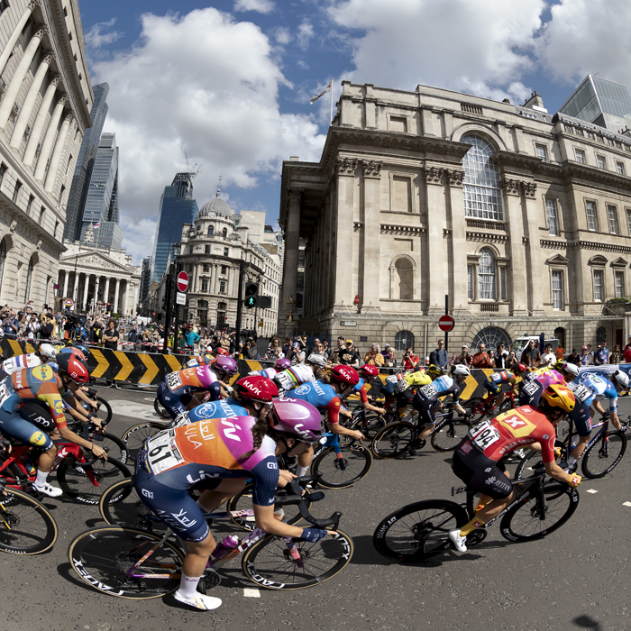 RideLondon Classique 2024 - The peloton takes a corner at Bank with the City of London in the background