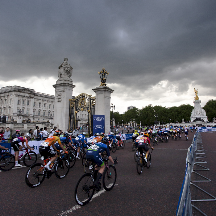 RideLondon Classique 2024 - The peloton passes by the ornate gates of Buckingham Palace under a stormy sky