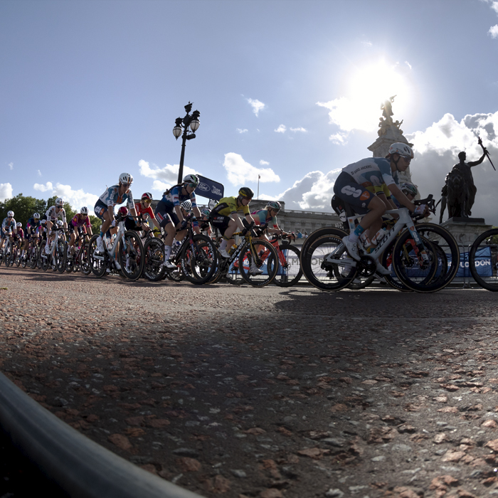 RideLondon Classique 2024 - The peloton pull onto The Mall in front of Buckingham Palace with the statues Winged Victory and Progress, parts of the Victoria Memorial, silhouetted against the sky