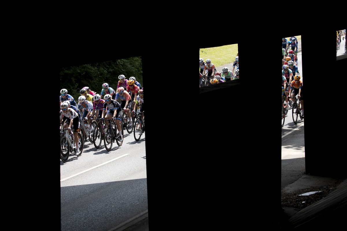 RideLondon Classique 2024 - Riders are framed by the supports of a concrete bridge in Witham