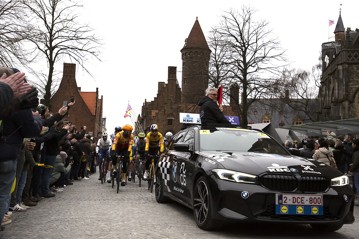 Ronde van Vlaanderen 2023 - The Race Director raises the flag out of the sunroof or his car at the neutral roll out in Brugge