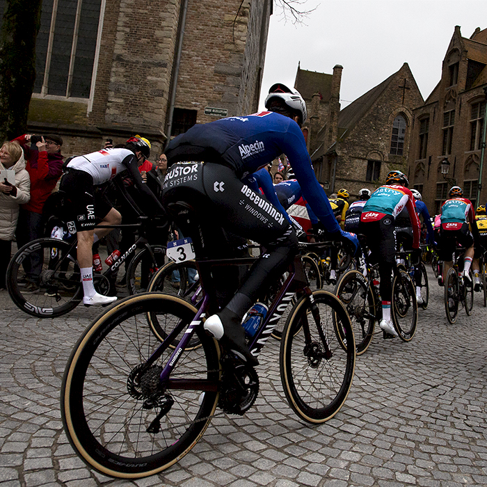 Ronde van Vlaanderen 2023 - The riders round a corner and move off through the cobbled streets of Brugge