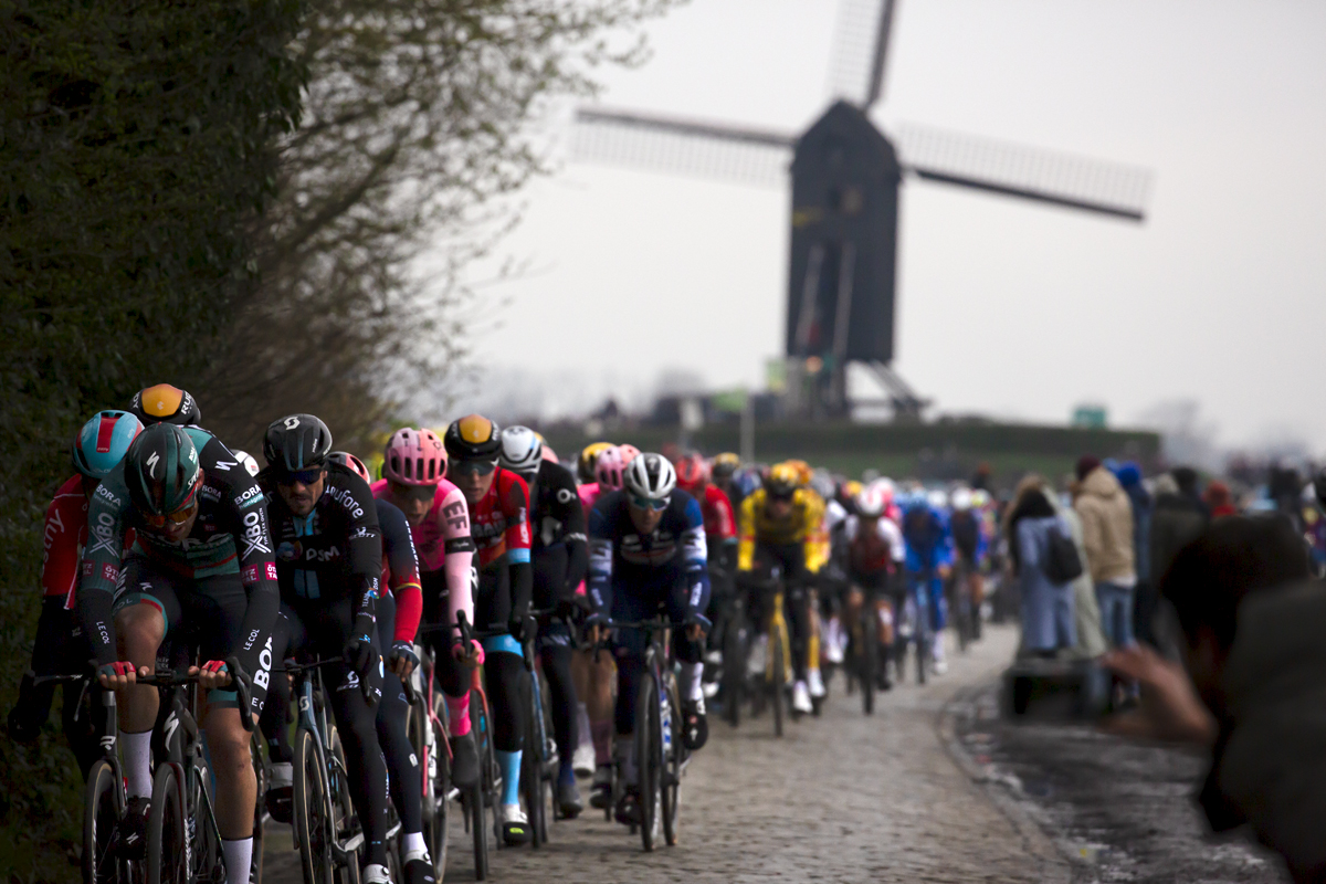 Ronde van Vlaanderen 2023 - The peloton on Huisepontweg with the Schietsjampettermolen windmill in the background