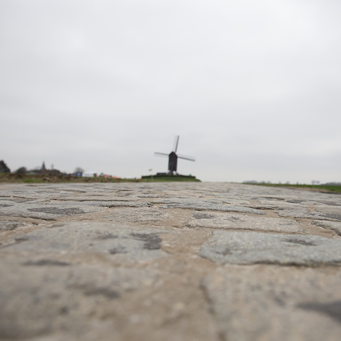 Ronde van Vlaanderen 2023 - Close up of the cobbles of Huisepontweg with the Schietsjampettermolen windmill in the distance