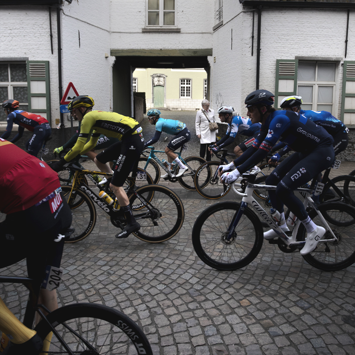 Ronde van Vlaanderen 2024 - Riders pass the gateway of a whitewashed building in Bazel