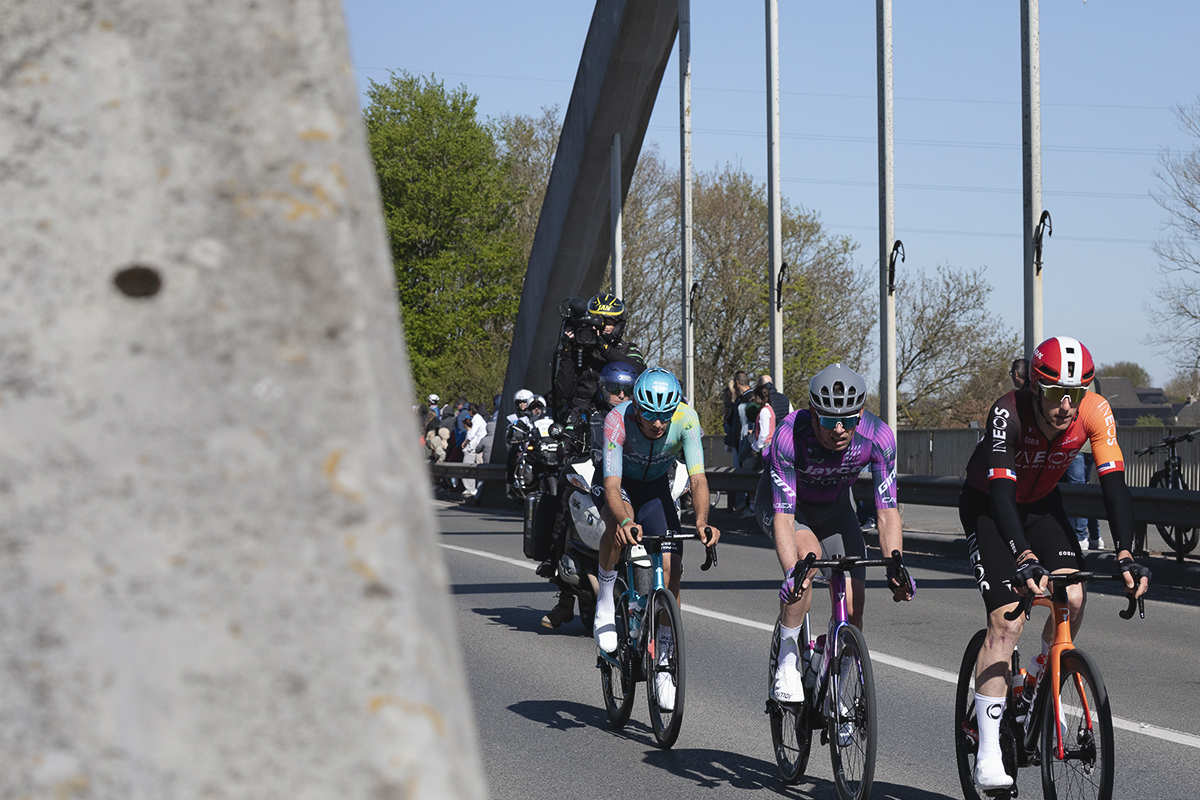 Ronde van Vlaanderen 2025 - A small group of riders cross a modern arched bridge