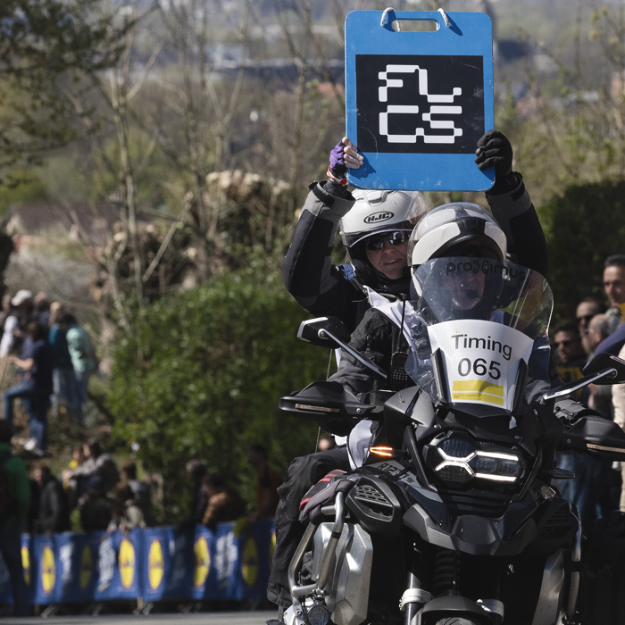 Ronde van Vlaanderen 2025 - The board indicating time splits is held aloft from the back of a motorbike