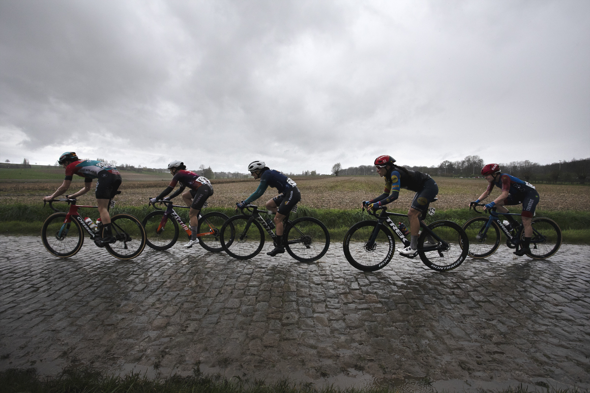 Ronde van Vlaanderen Vrouwen 2024 - Riders wearing rain jackets as they race on wet cobbles on Mariaborrestraat