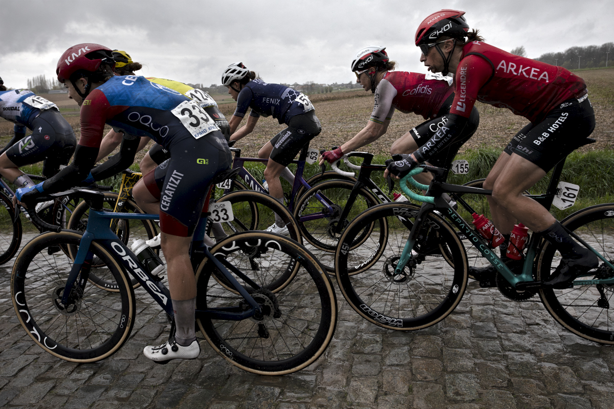 Ronde van Vlaanderen Vrouwen 2024 - A side view of riders on the wet cobbles of Mariaborrestraat