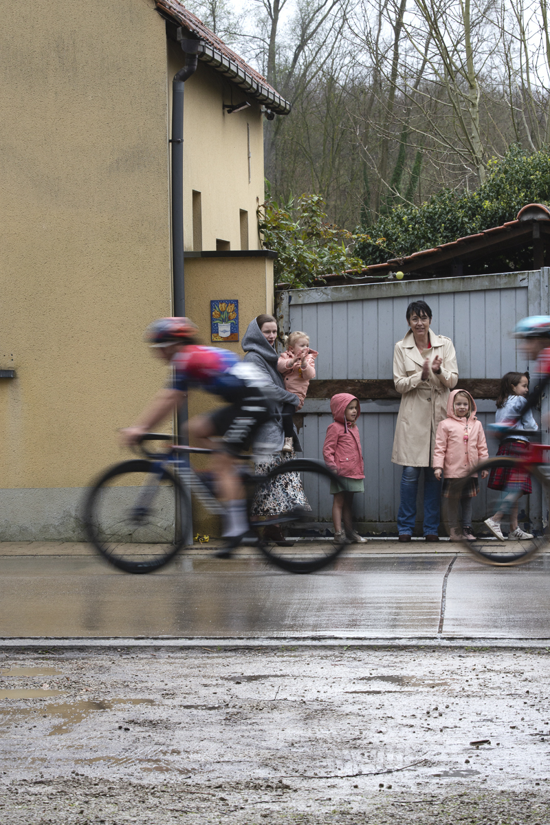 Ronde van Vlaanderen Vrouwen 2024 - Riders speed past a group of young children and their mothers watching the race