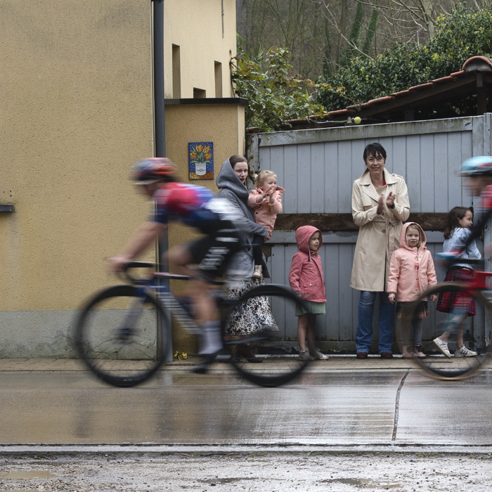Ronde van Vlaanderen Vrouwen 2024 - Riders speed past a group of young children and their mothers watching the race