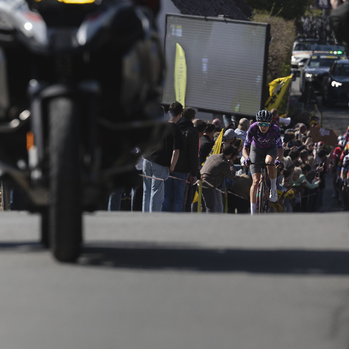 Ronde van Vlaanderen Vrouwen 2025 - Quinty Ton on Berendries, crowds in the background gather beneath a large screen showing the men’s race
