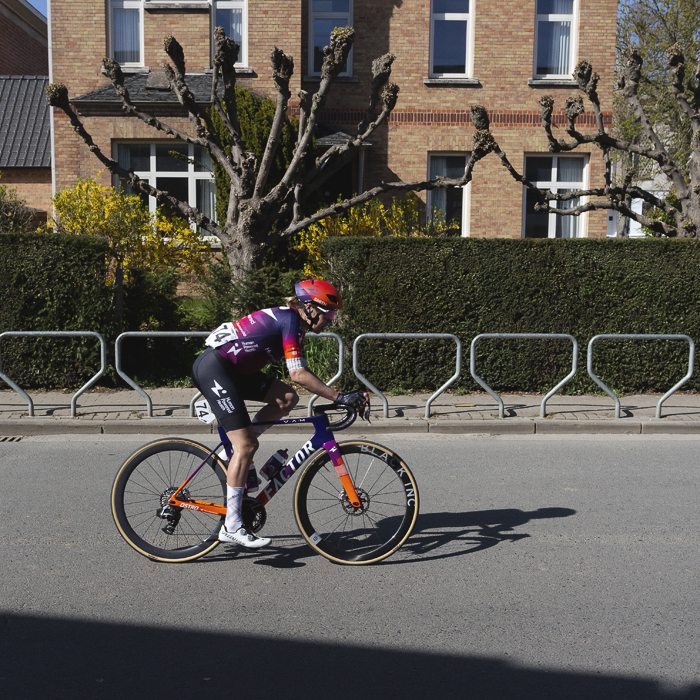 Ronde van Vlaanderen Vrouwen 2025 - Romy Kasper rides in front of a building with neatly pruned trees