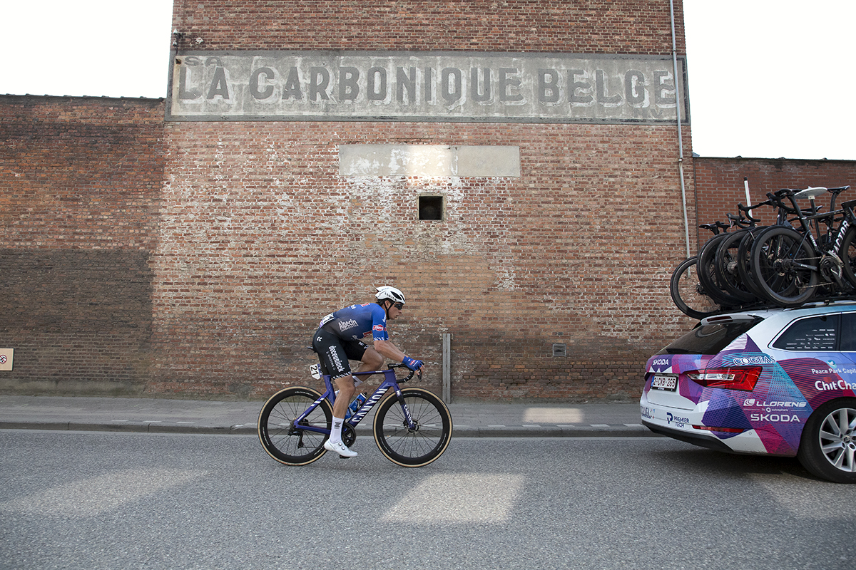 Scheldeprijs 2023 - Jasper Philipsen of Alpecin-Deceuninck passes a worn sign on an old brick building that reads La Carbonique Belge