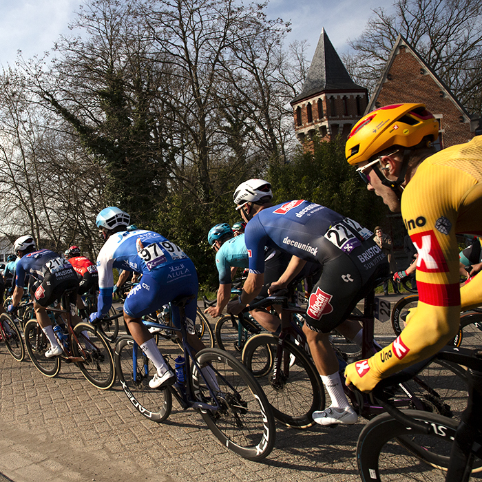 Scheldeprijs 2023 - The peloton hugs the inside of a bend as it passes a gatehouse to Kasteel Calesberg