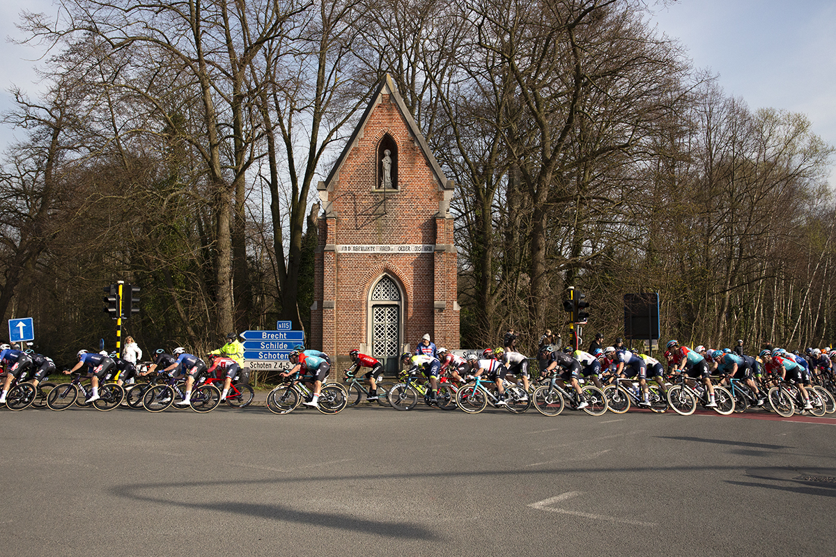 Scheldeprijs 2023 - The peloton pass a Kapel on the corner of a junction and accelerate towards the finish