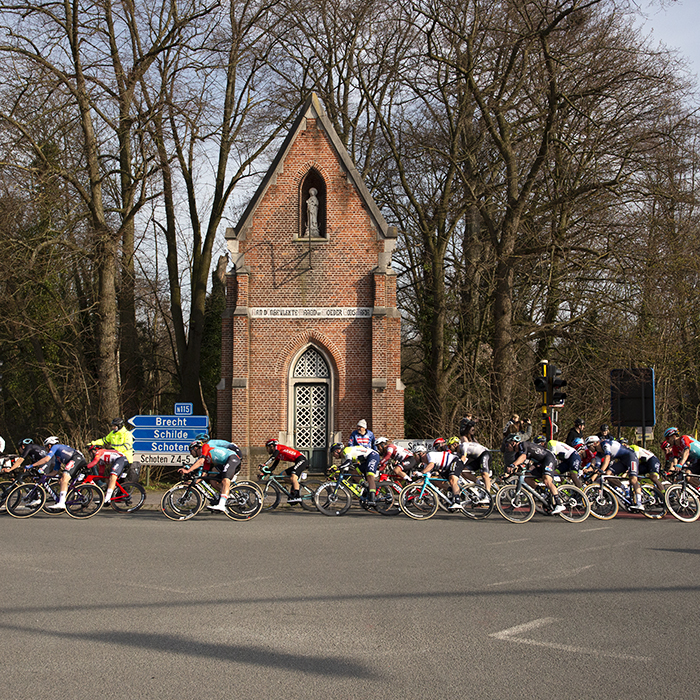 Scheldeprijs 2023 - The peloton pass a Kapel on the corner of a junction and accelerate towards the finish