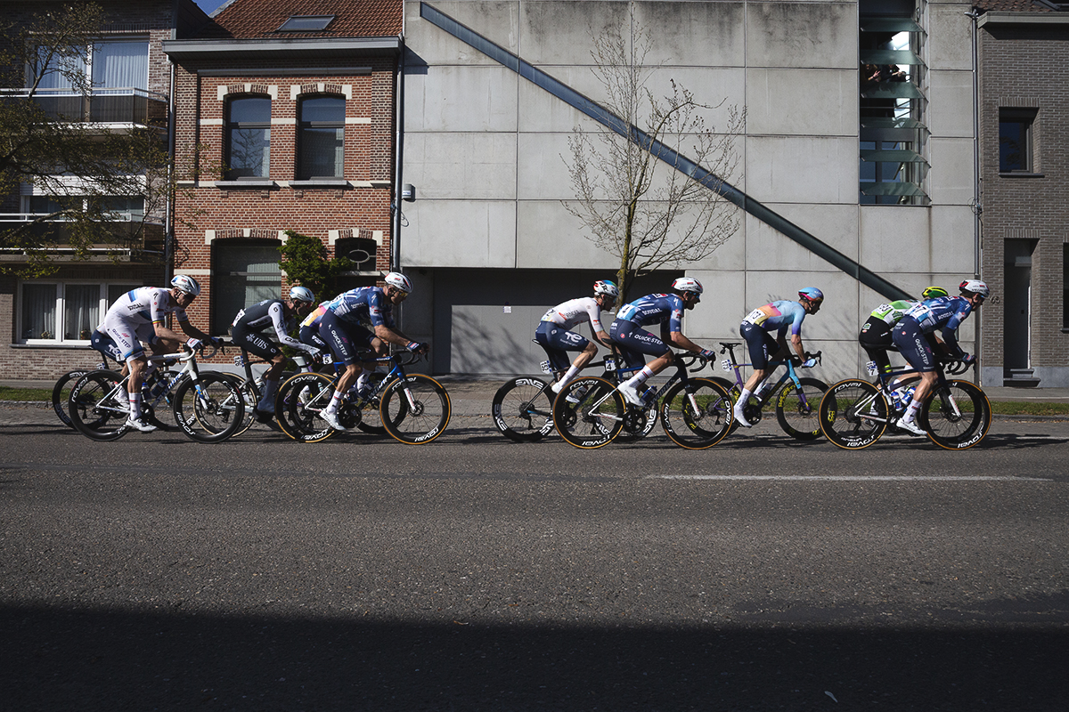 Scheldeprijs 2025 - An elite group of riders race past the brutalist frontage of a modern house in Schoten