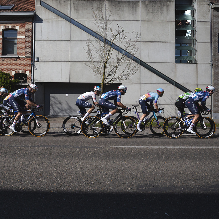 Scheldeprijs 2025 - An elite group of riders race past the brutalist frontage of a modern house in Schoten