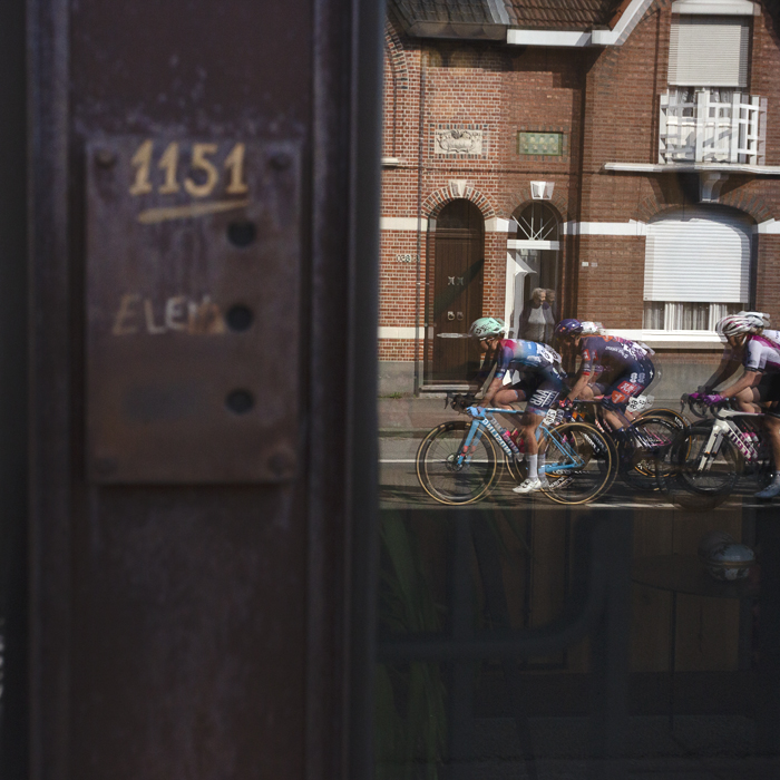 Scheldeprijs Vrouwen 2025 - Riders are reflected in the rusty door of an artisan metalworker