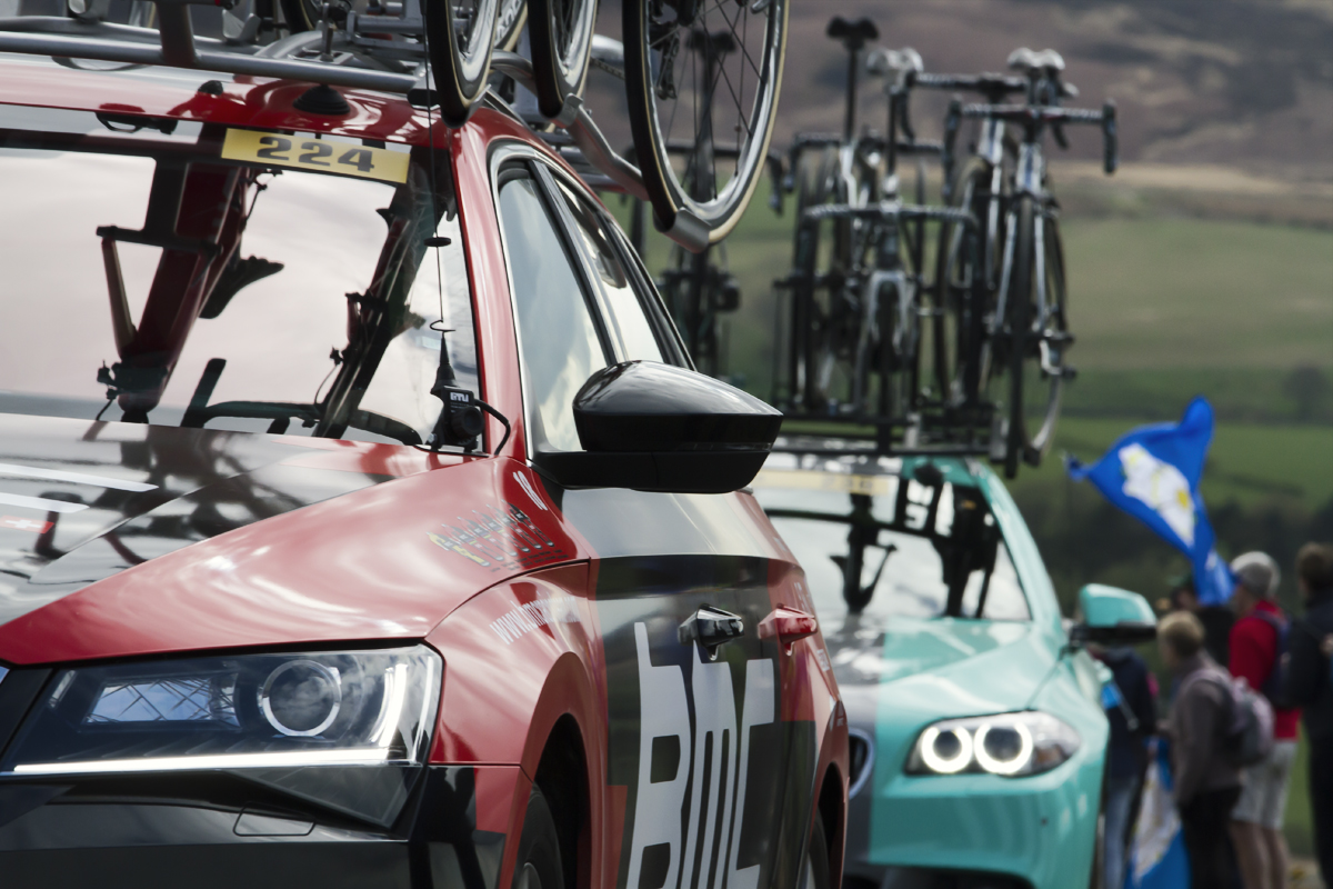 Tour de Yorkshire 2017 - Team Cars pass fans holding Yorkshire flags