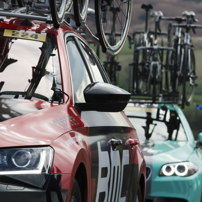 Tour de Yorkshire 2017 - Team Cars pass fans holding Yorkshire flags