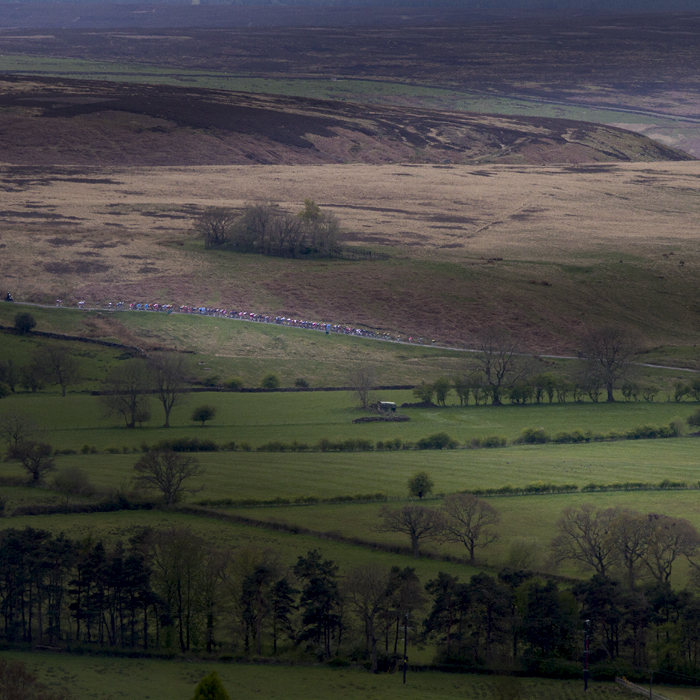 Tour de Yorkshire 2017 - the peloton is seen on a hill in the distance at Goathland