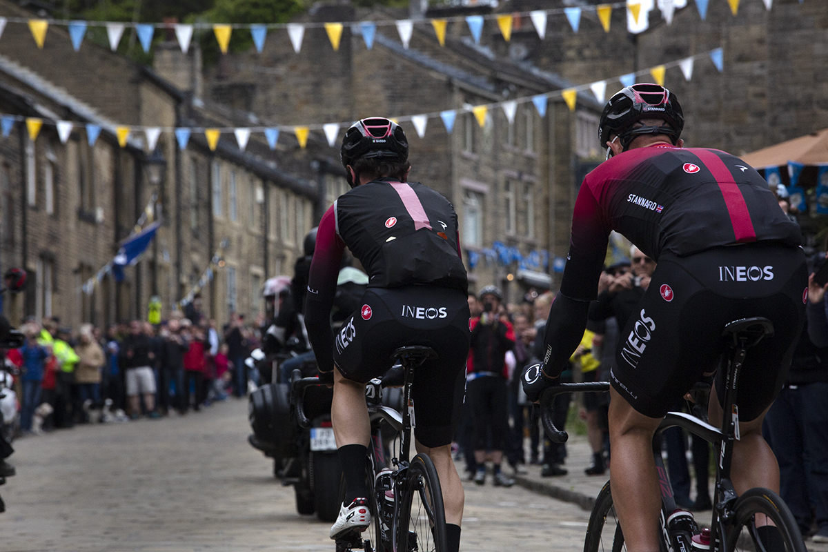 Tour de Yorkshire 2019 - Rear shot of INEOS riders making their way onto the climb in Haworth with Tour de Yorkshire bunting visible