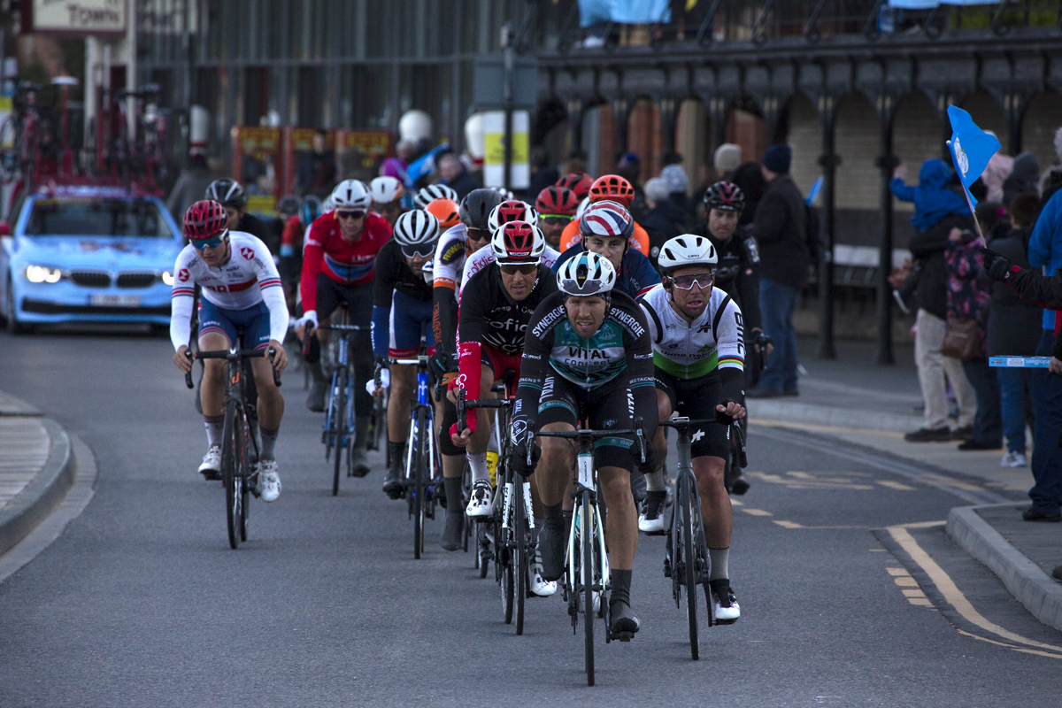 Tour de Yorkshire 2019 - A group of riders makes their way down the sea front in Scarborough as a fan waves a Yorkshire flag