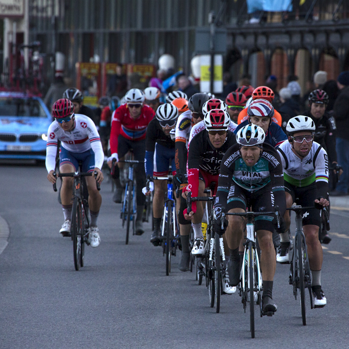 Tour de Yorkshire 2019 - A group of riders makes their way down the sea front in Scarborough as a fan waves a Yorkshire flag