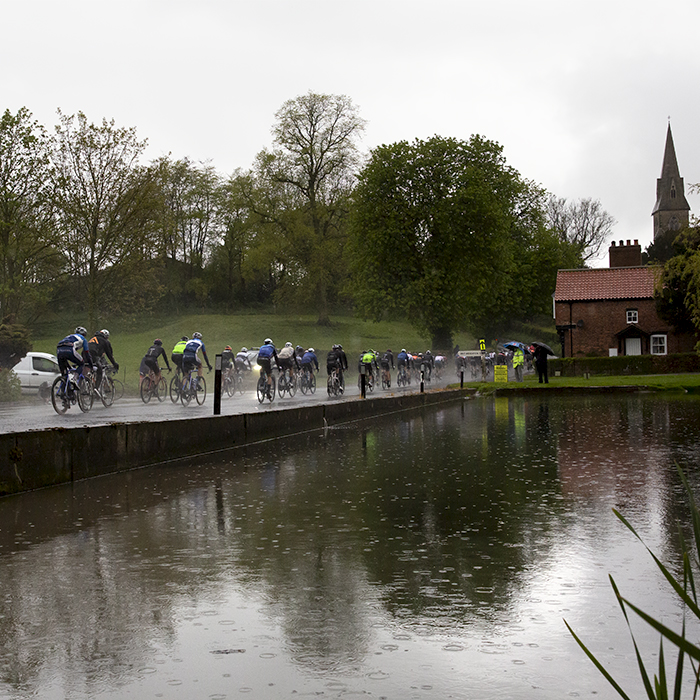 Tour de Yorkshire 2019 - The peloton pass by a pond in Warter as the rains falls